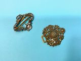 two antique brooches on a blue background