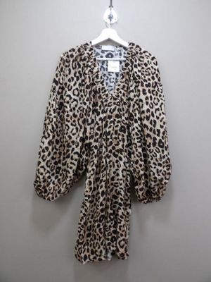 a leopard print robe hangs on a hanger against a wall