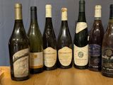 several bottles of wine are lined up on a wooden table