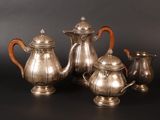 three pieces of silver tea and coffee set on a black surface