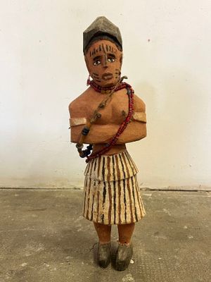 a wooden statue of a man in a skirt and hat