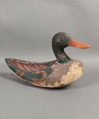 an old wooden duck sitting on a gray surface