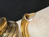 a gold tea pot sitting on a table with a black background