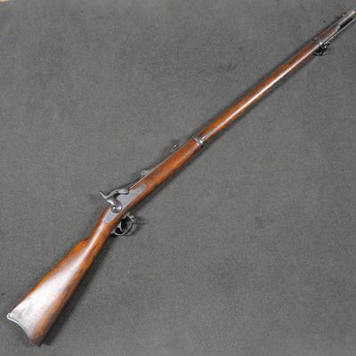 an old rifle with a wooden handle on a gray surface