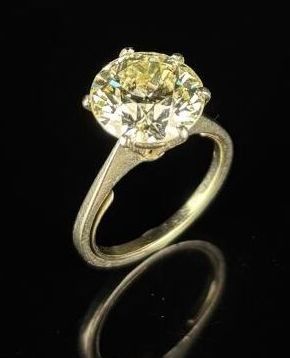 un gros plan d'une bague sertie d'un diamant jaune sur une surface noire