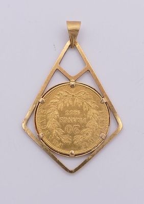 une pièce d'or dans un pendentif en forme de losange posé sur une surface blanche