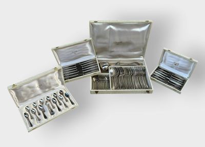 Plusieurs pièces d'argenterie sont disposées dans un coffret en argent posé sur une surface blanche