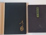 an open book sitting on top of a white table next to a black book