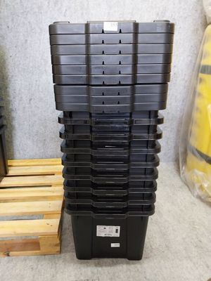 une pile de bacs en plastique noir posée sur une palette en bois