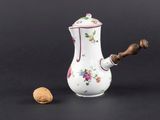 un petit vase blanc avec des fleurs et une noix posée à côté