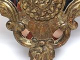 a mirror with a gold decoration on it on a table
