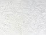 white embroidered tablecloth with a floral design on a white background