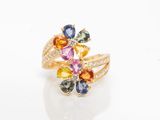 un gros plan d'une bague ornée de pierres multicolores sur un fond blanc