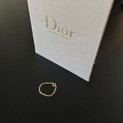 une bague en or repose sur une table noire, à côté d'une boîte blanche