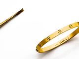 un bracelet en or et une broche sur un fond blanc