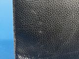 a close up of a black leather purse on a blue background