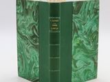 an old book with a green cover sitting on top of a white table