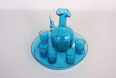 un pichet en verre bleu et des verres posés sur une assiette