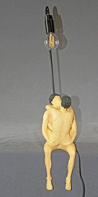 une figurine représentant un homme assis sur une lampe