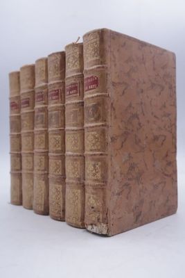 several old books are stacked on top of each other on a white surface