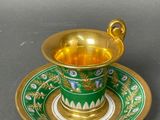an image of a green and gold cup and saucer on a saucer