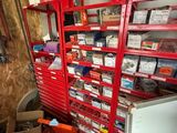 a red shelving in a garage with a refrigerator and other items