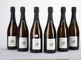 six bouteilles de vin posées sur une table à côté d'une bouteille de vin