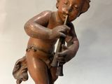 une statue représentant un garçon jouant de la flûte au sommet d'un rocher