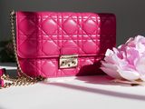 a pink purse sitting on a table next to a pink flower