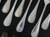 a lot of silver spoons and forks laid out on a table