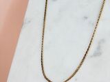 un collier à chaîne en or posé sur une surface en marbre