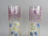 deux vases avec des fleurs peintes dessus, posés sur une table
