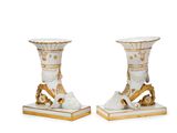 two white vases with gold decorations on them