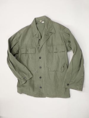 a green jacket is hanging on a white wall