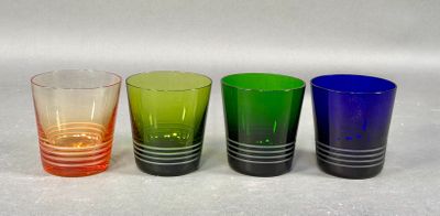 four different colored glasses lined up on a white surface