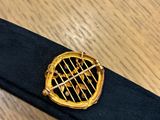 gold tennis racket pin on black leather belt