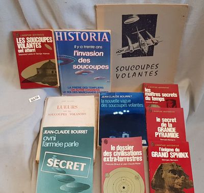 several books on a bed with a white sheet in the background