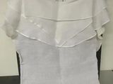 a white top with ruffles on it on a hanger