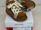 des chaussures de bébé marron et blanches ornées d'un imprimé léopard, posées sur une boîte