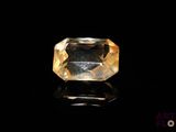a yellow sapphire stone on a black surface