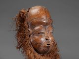 a wooden mask with long hair on a gray background
