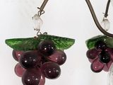 a glass vase with a bunch of grapes hanging from it