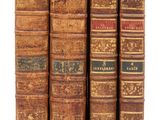 quatre vieux livres sont alignés sur une surface blanche