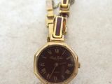 a close up of a watch on a white surface with a chain around it