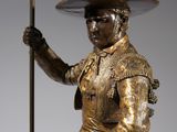 bronze statue of a man riding a horse with a flag on top of it