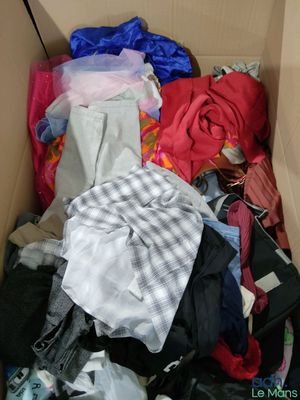 une boîte en carton remplie de vêtements, ainsi que des vêtements éparpillés sur le sol