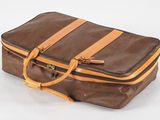une valise marron posée sur une surface blanche
