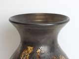a vase that is sitting on a table with a white wall in the background