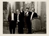 four men in suits standing next to each other in a room