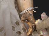 a close up of a doll ' s hand holding a teddy bear